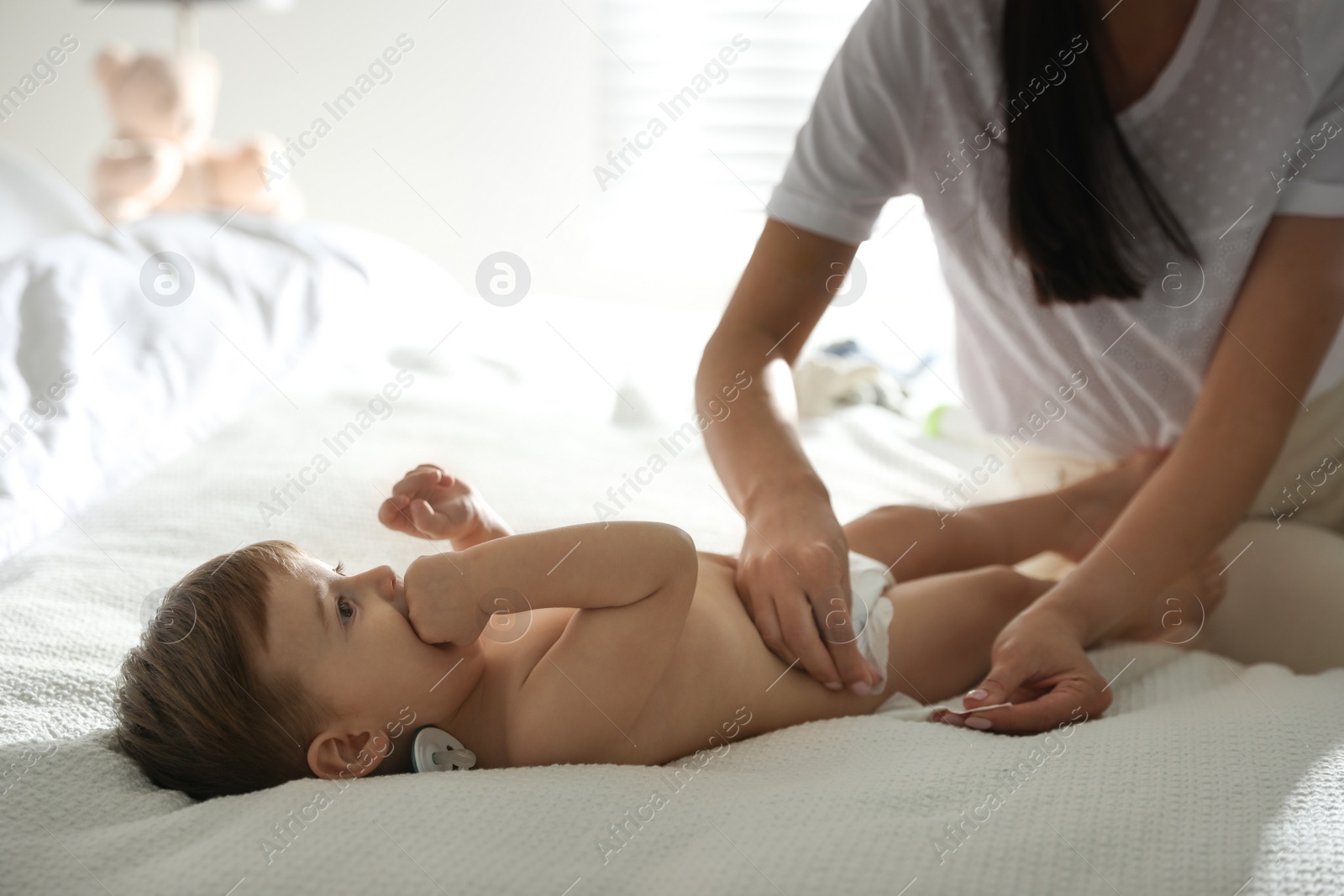 Photo of Mother changing baby's diaper on bed at home