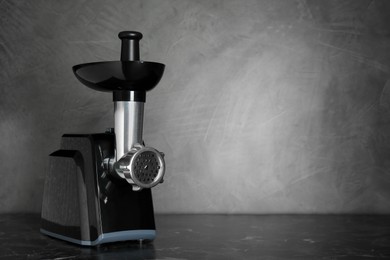 Photo of Modern electric meat grinder on black table. Space for text