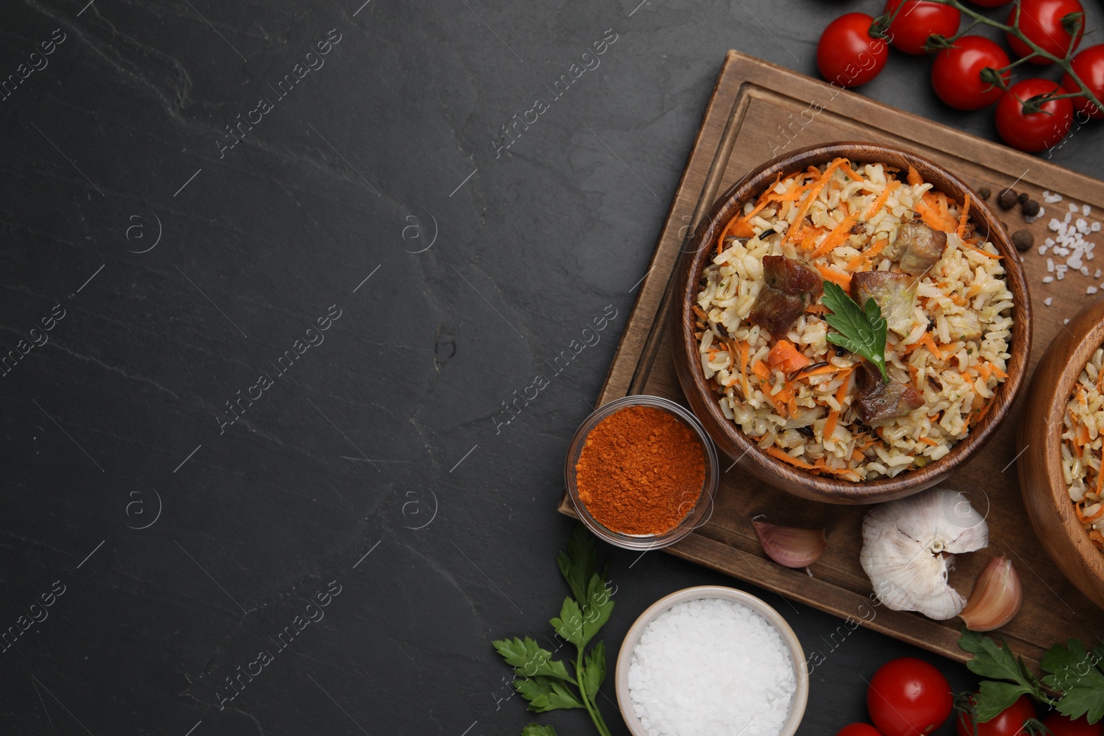 Photo of Delicious pilaf and products on black table, flat lay. Space for text