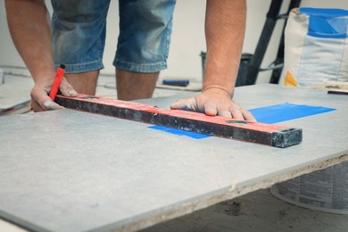 Photo of Worker making socket hole in tile indoors, closeup