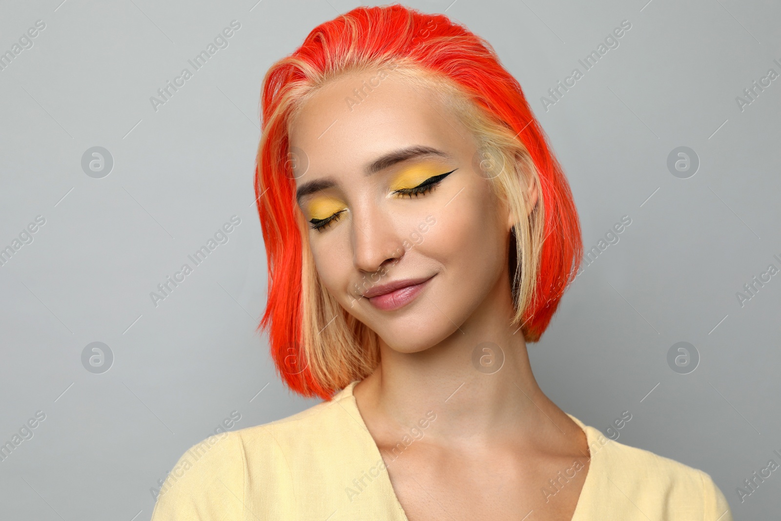 Photo of Beautiful young woman with bright dyed hair on light grey background