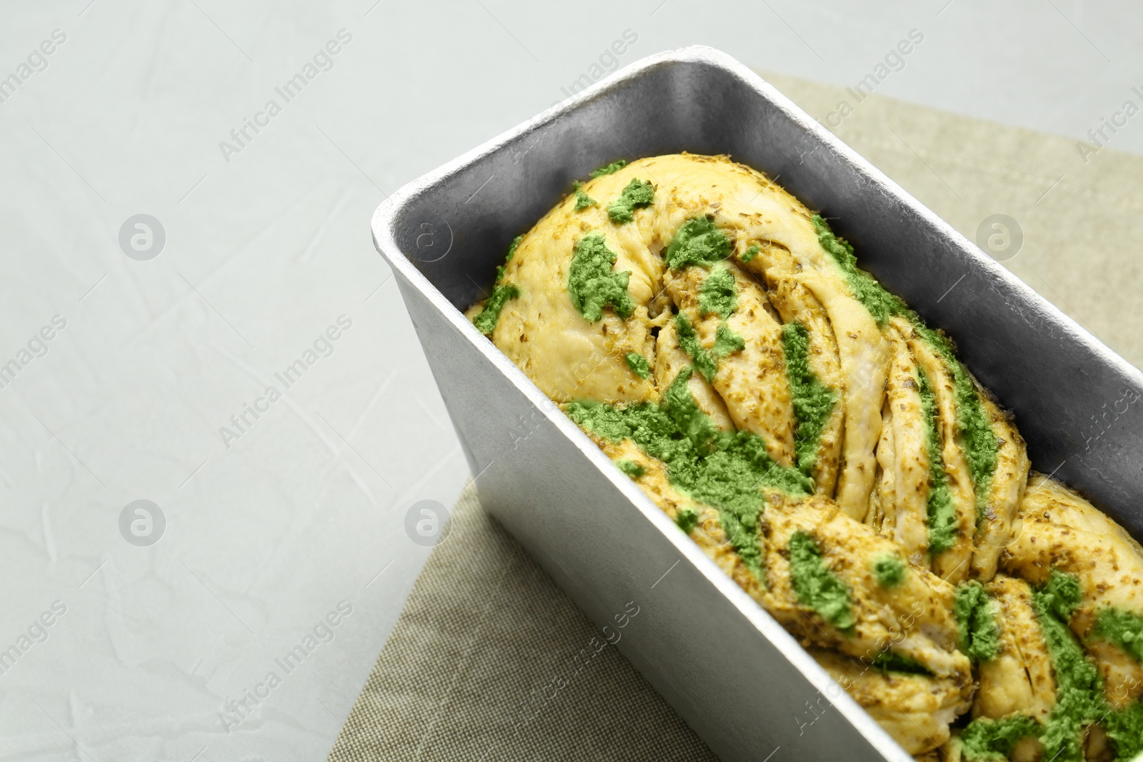 Photo of Uncooked pesto bread in baking dish on light table, space for text