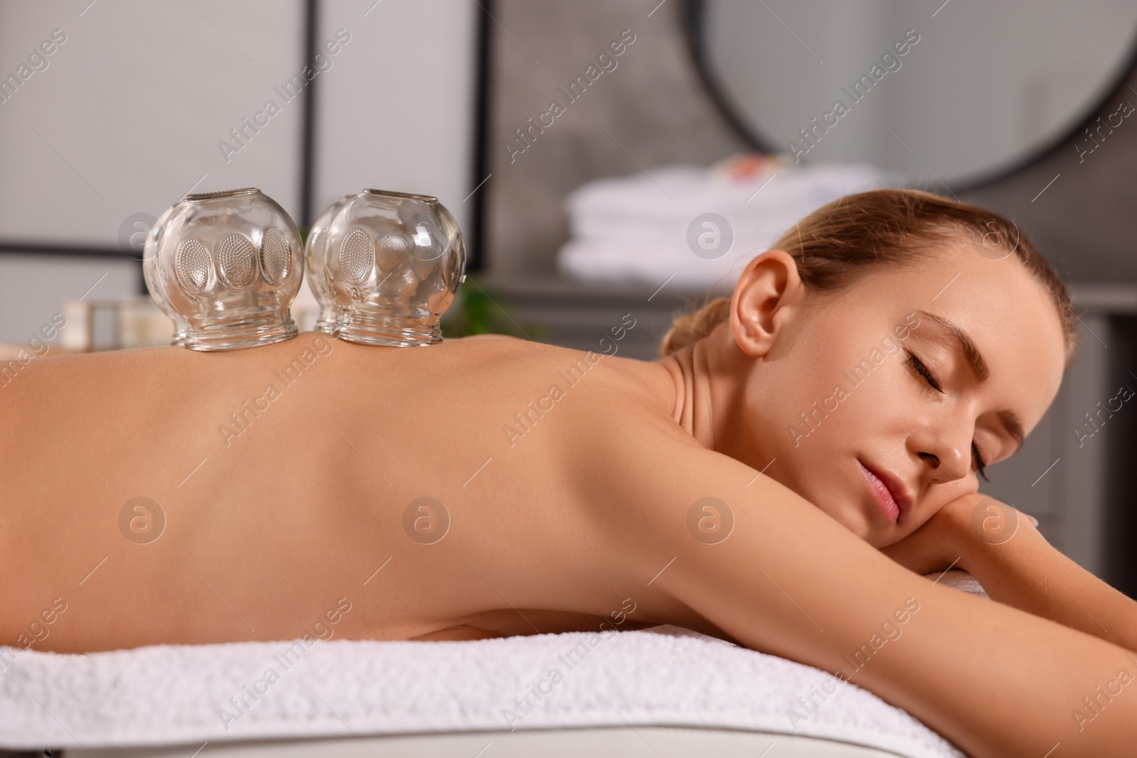 Photo of Cupping therapy. Woman with glass cups on massage couch in spa salon