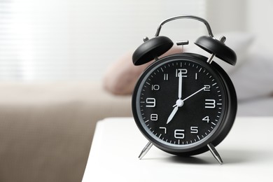 Photo of Black alarm clock on white wooden nightstand in bedroom, space for text