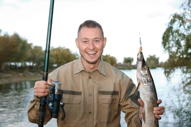 Man with rod and catch fishing at riverside. Recreational activity