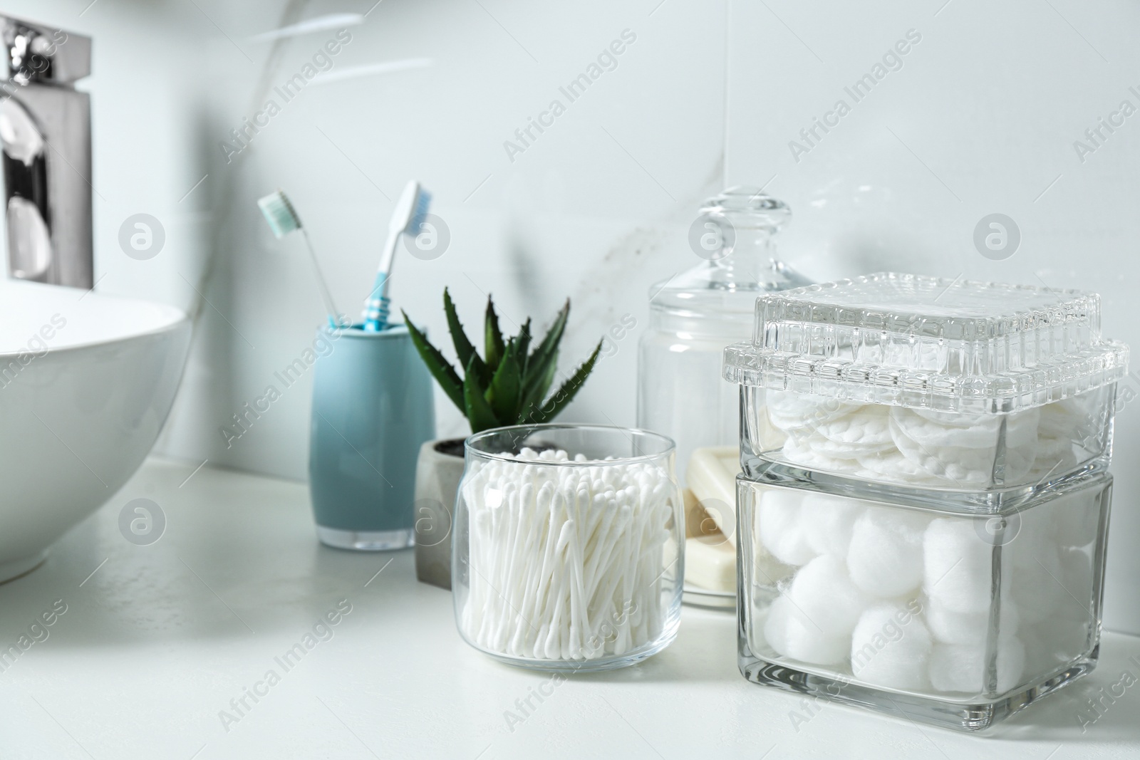 Photo of Cotton swabs, pads and balls on white countertop in bathroom