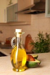 Photo of Fresh avocado and jugcooking oil on beige marble table in kitchen