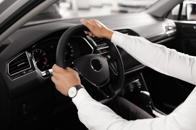 Photo of Young man testing new car in salon