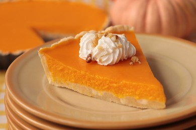 Photo of Stacked plates with piece of fresh homemade pumpkin pie with whipped cream on table