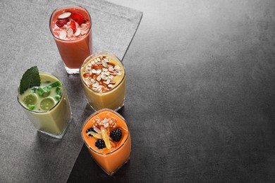 Photo of Many different delicious smoothies on grey table, above view. Space for text