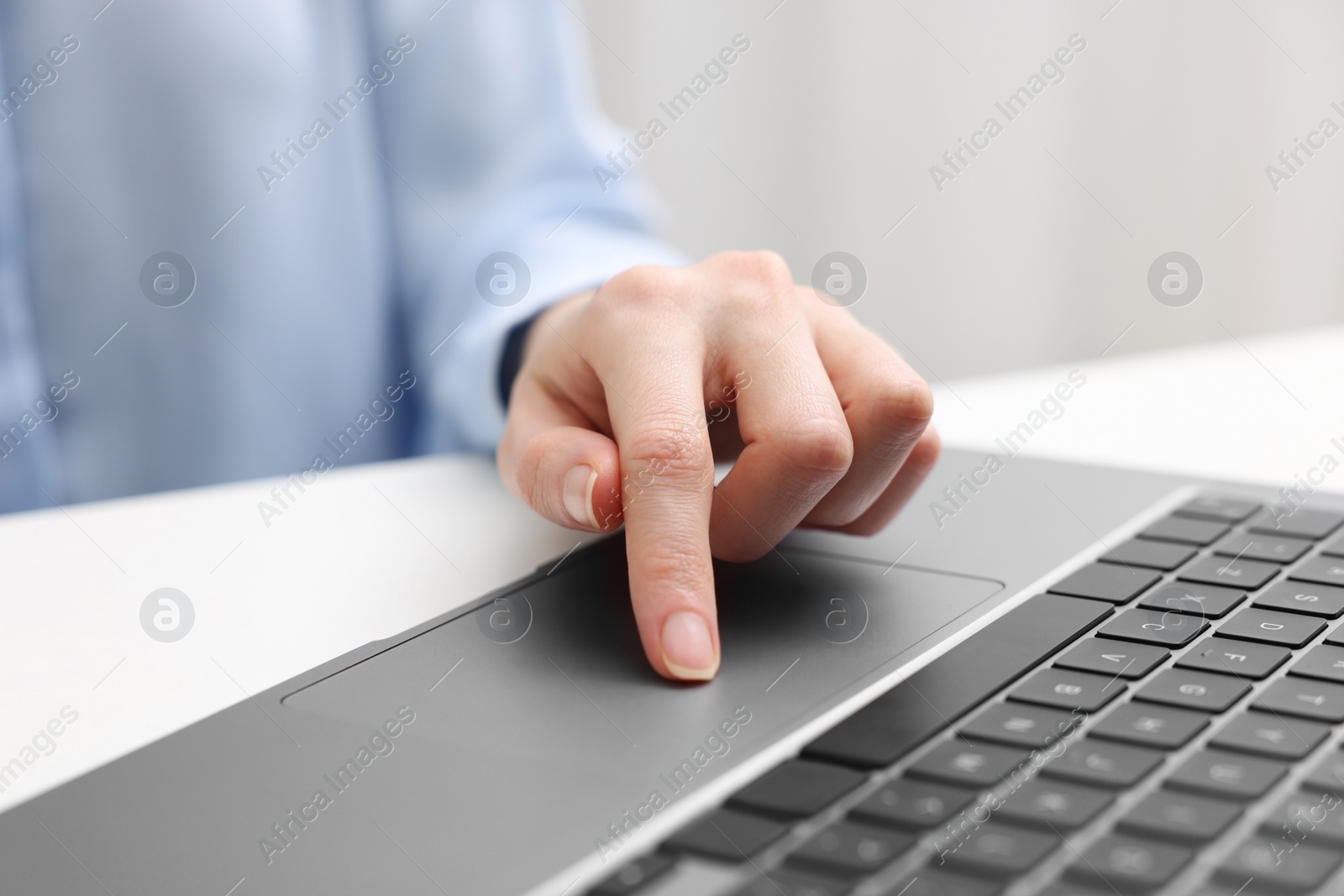 Photo of E-learning. Woman using laptop at white table indoors, closeup