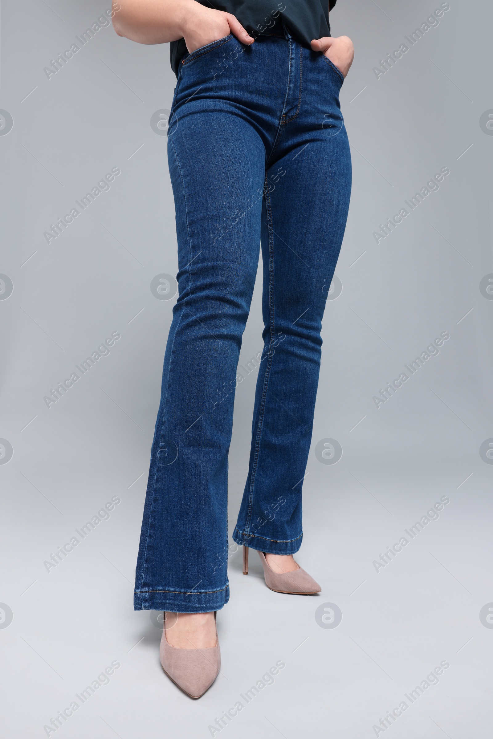 Photo of Woman in stylish jeans on grey background, closeup