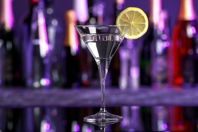 Photo of Martini glass of refreshing cocktail and lemon slice on mirror surface