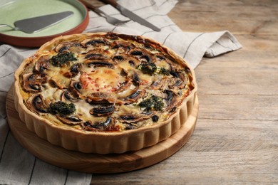 Photo of Delicious quiche with mushrooms on wooden table, space for text