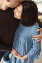 Young husband hugging his pregnant wife at home