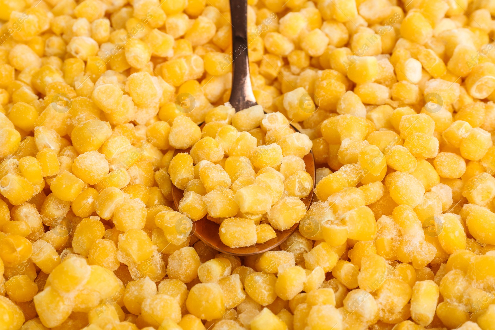 Photo of Frozen corn and spoon, closeup. Vegetable preservation