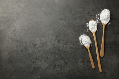 Photo of Baking powder in spoons on grey textured table, flat lay. Space for text