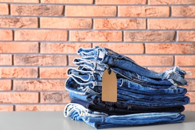 Photo of Stack of jeans on table against brick wall background