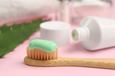 Photo of Toothbrush with aloe toothpaste on pink background, closeup