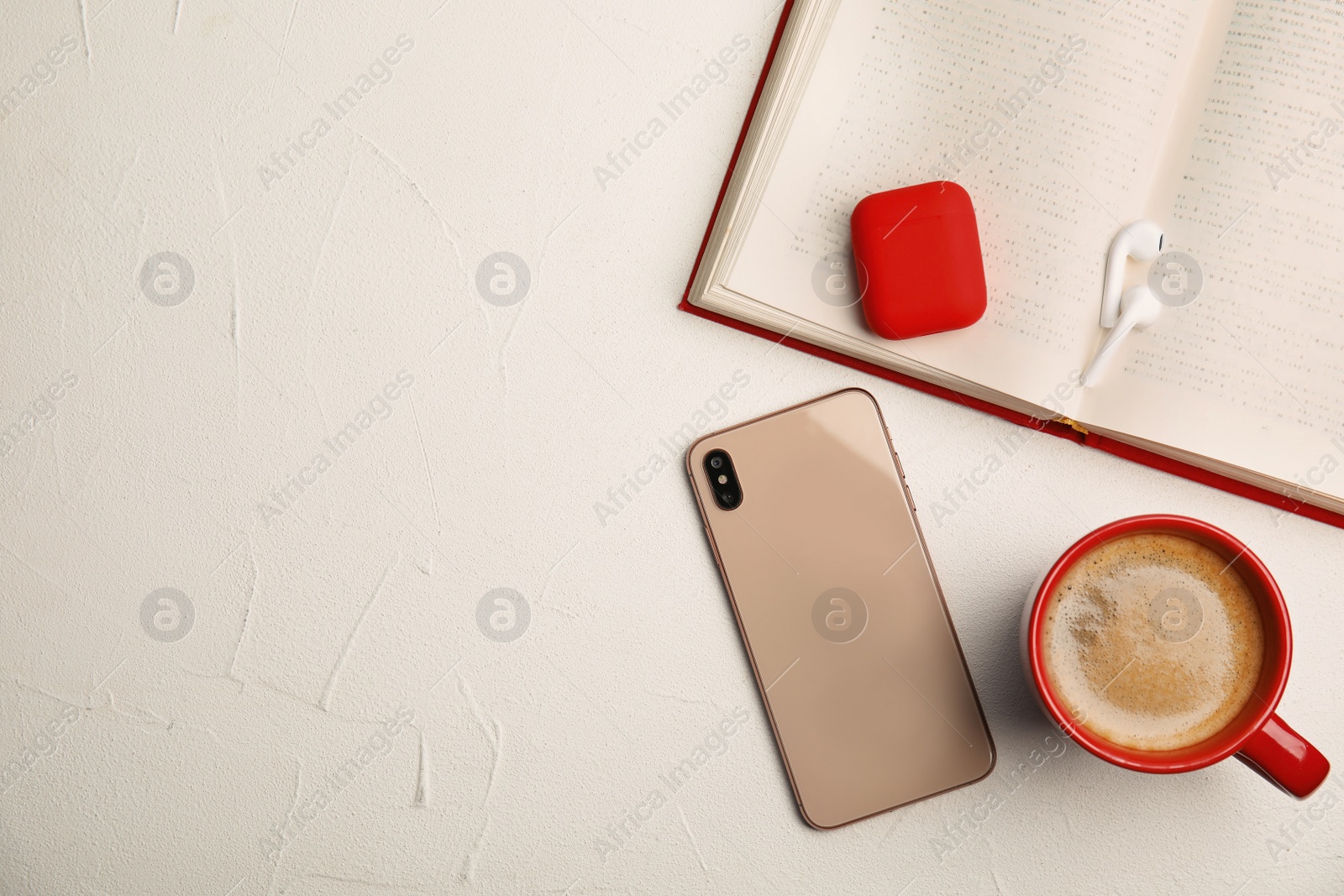 Photo of Book, coffee, earphones and mobile phone on white table, flat lay. Space for text