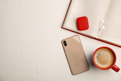 Photo of Book, coffee, earphones and mobile phone on white table, flat lay. Space for text