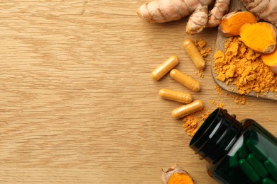 Photo of Aromatic turmeric powder, raw roots and pills on wooden table, flat lay. Space for text