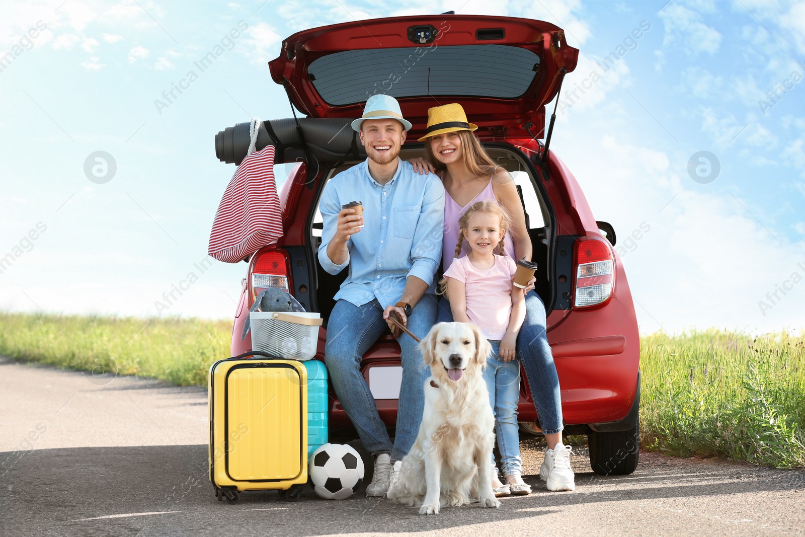 Photo of Young family with luggage and dog near car trunk outdoors