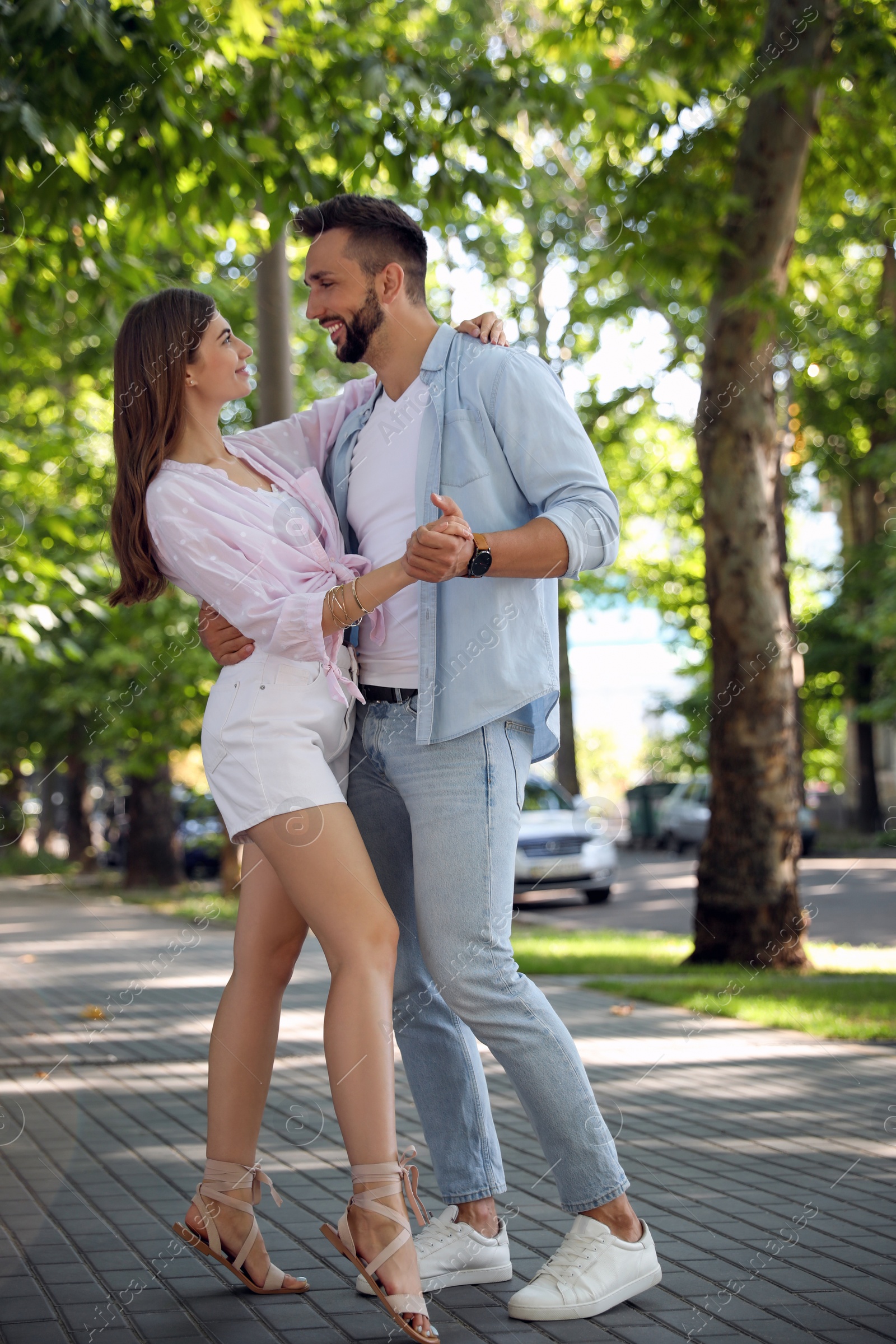 Photo of Lovely young couple dancing together outdoors on sunny day