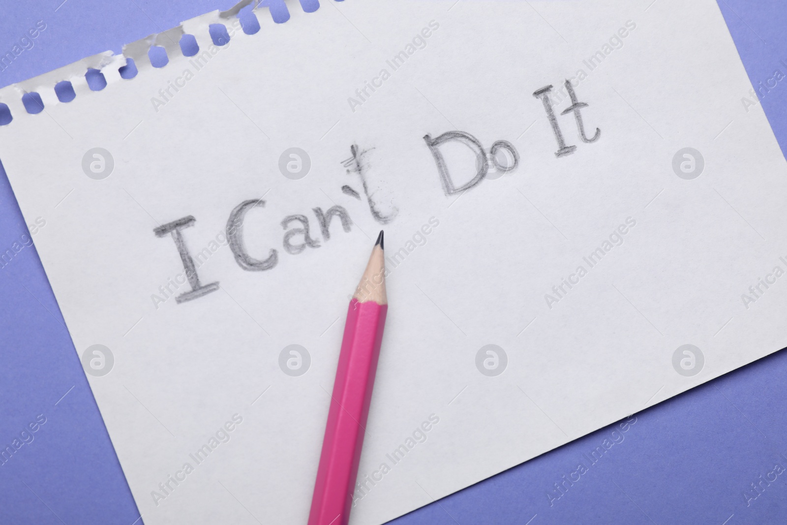 Photo of Motivation concept. Paper with changed phrase from I Can't Do It into I Can Do It by erasing letter T on violet background, top view