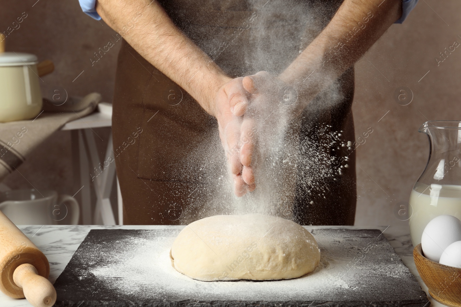 Photo of Male baker preparing bread dough at table, closeup