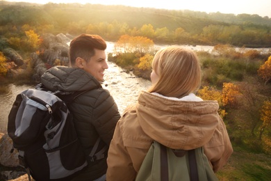 Photo of Couple of hikers with travel backpacks sitting on steep cliff