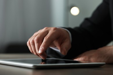 Photo of Closeup view of man using new tablet at desk indoors