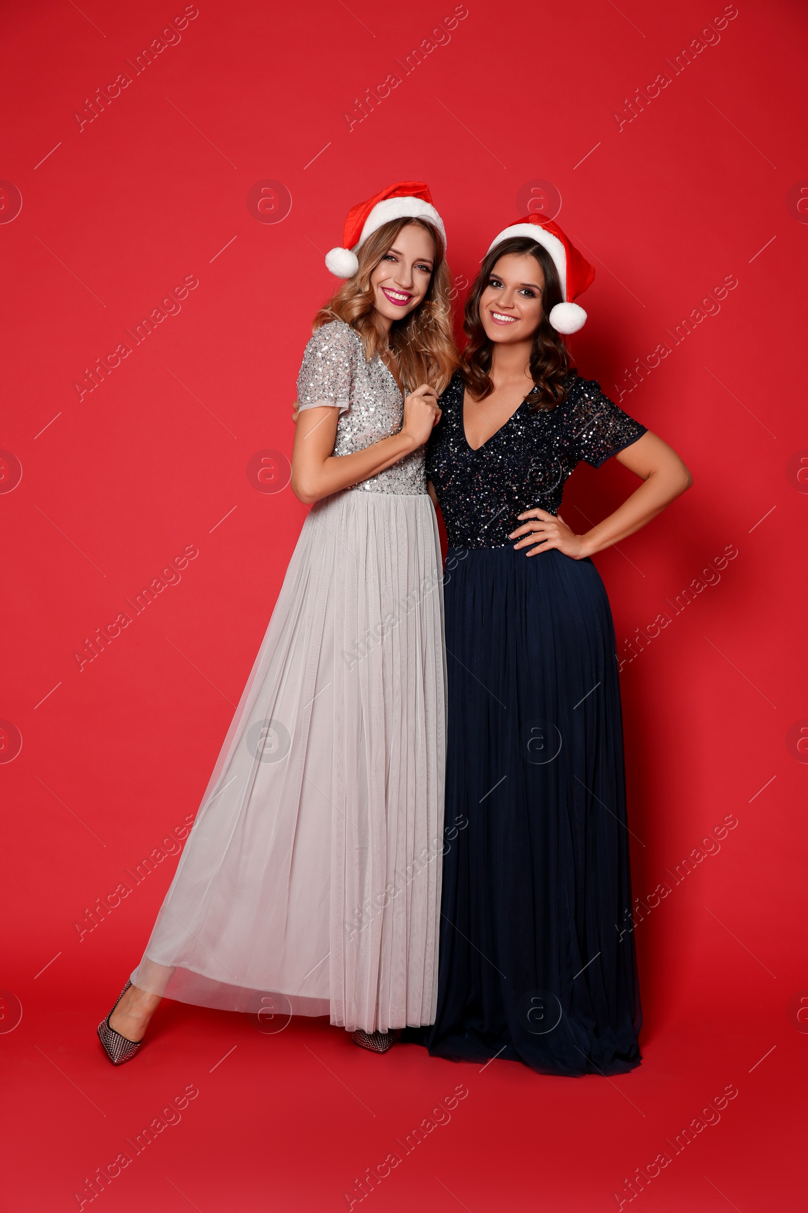Photo of Beautiful women in Santa hats on red background. Christmas party