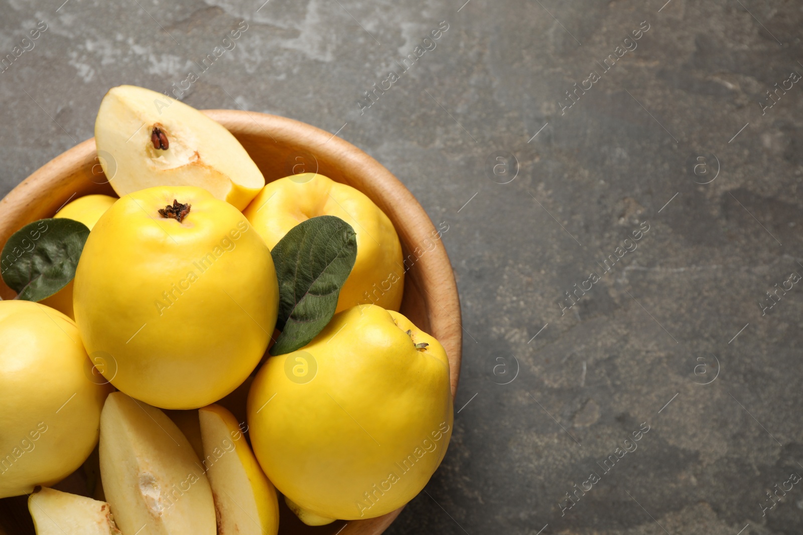 Photo of Fresh ripe organic quinces with leaves on grey table, top view. Space for text