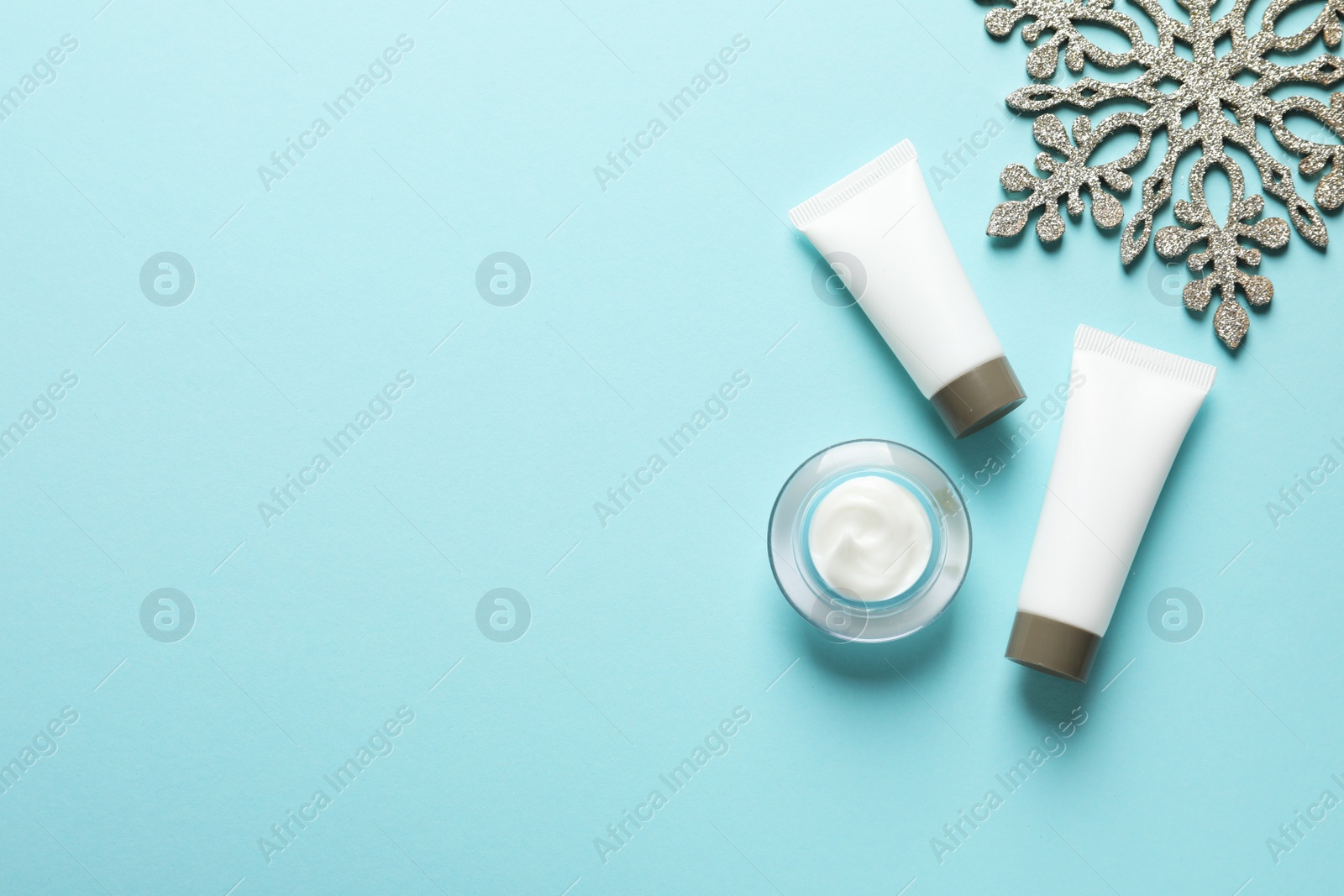 Photo of Set of cosmetic products on blue background, flat lay with space for text. Winter care