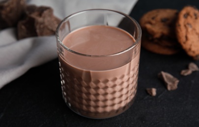 Glass of tasty chocolate milk on dark table, closeup. Dairy drink