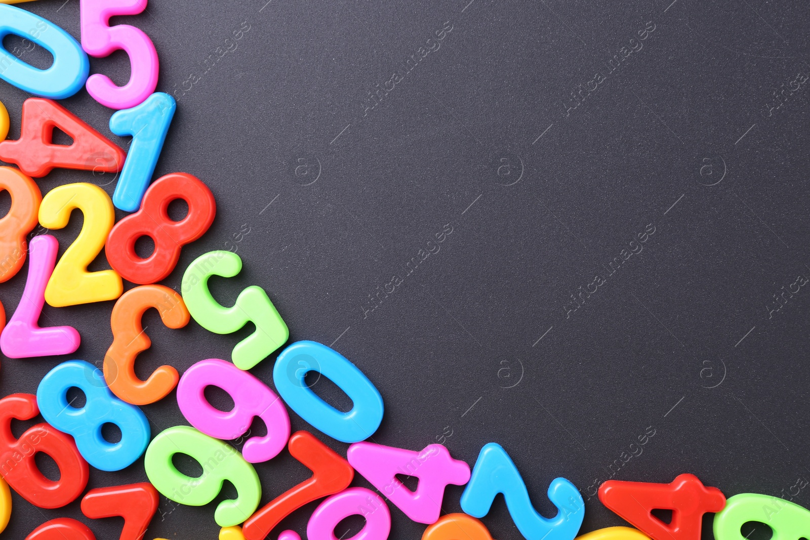 Photo of Colorful numbers on dark gray background, flat lay. Space for text