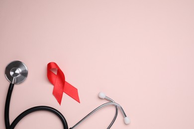 Photo of Red ribbon and stethoscope on pink background, flat lay with space for text. AIDS disease awareness