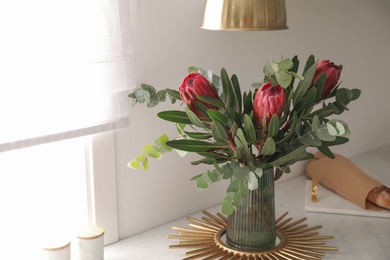 Photo of Bouquet with beautiful protea flowers on countertop in kitchen. Interior design