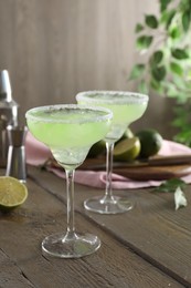 Delicious Margarita cocktail in glasses on wooden table