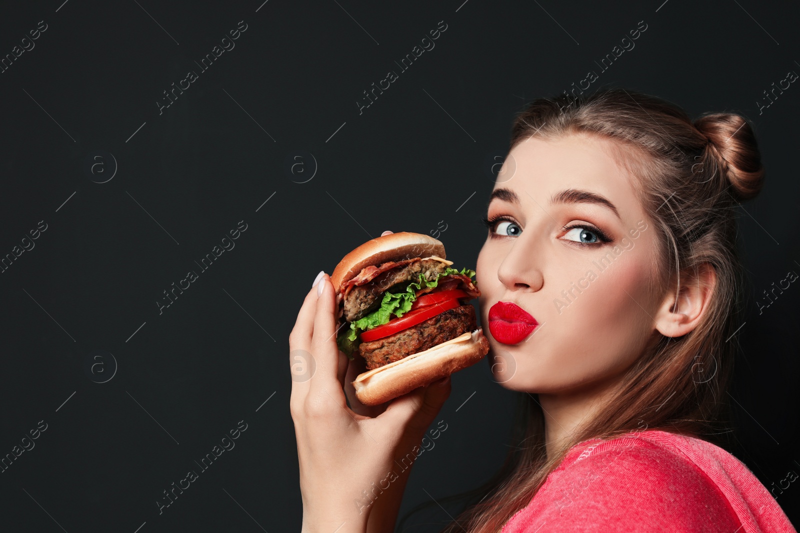 Photo of Pretty woman with tasty burger on black background. Space for text