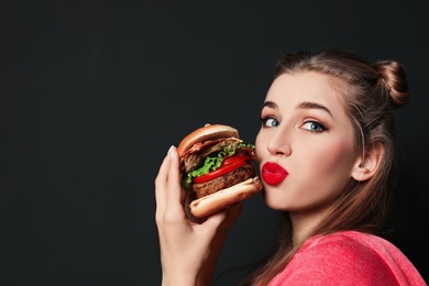 Pretty woman with tasty burger on black background. Space for text