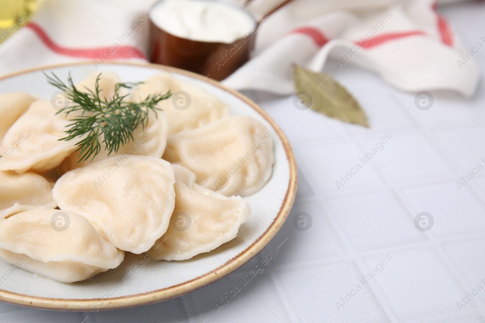 Photo of Cooked dumplings (varenyky) with tasty filling and dill on white table, closeup. Space for text