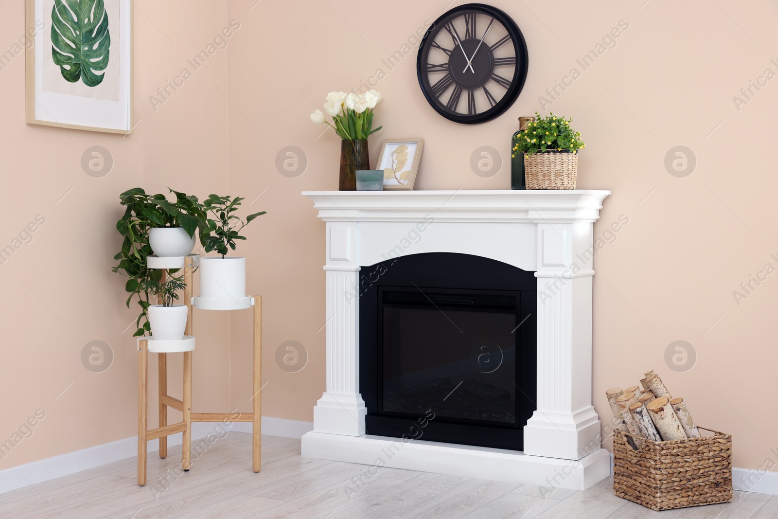 Photo of Stylish fireplace near potted plants and firewood in cosy living room