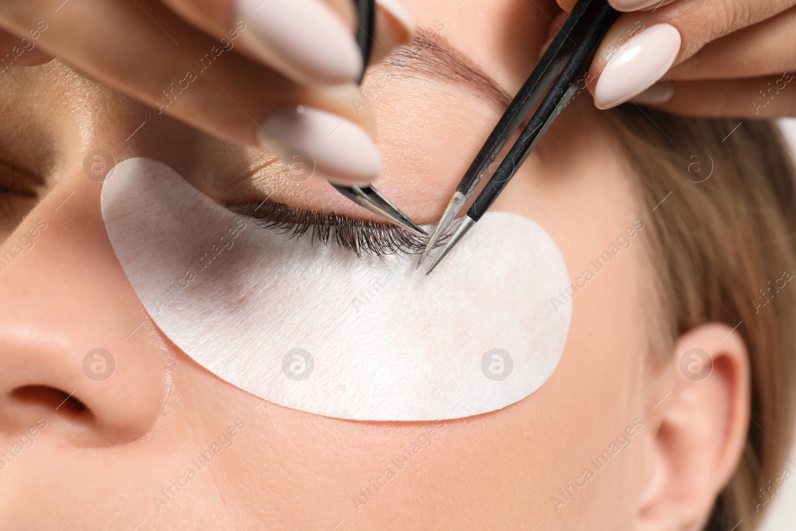 Photo of Young woman undergoing eyelash extension procedure, closeup