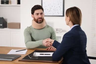 Lawyer shaking hands with injured client in office