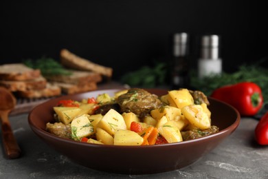 Tasty cooked dish with potatoes in earthenware on grey table