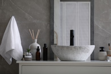 Stone vessel sink with faucet and toiletries on white countertop in bathroom