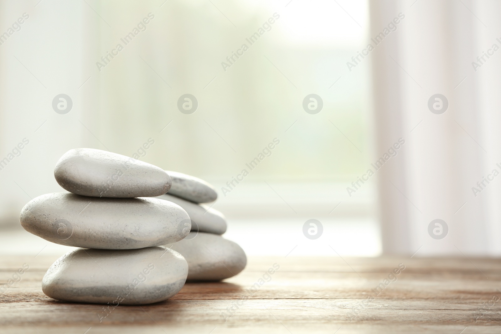 Photo of Spa stones on table against blurred background. Space for text