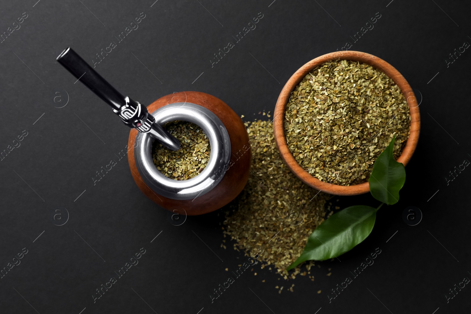 Photo of Calabash with mate tea and bombilla on black table, flat lay